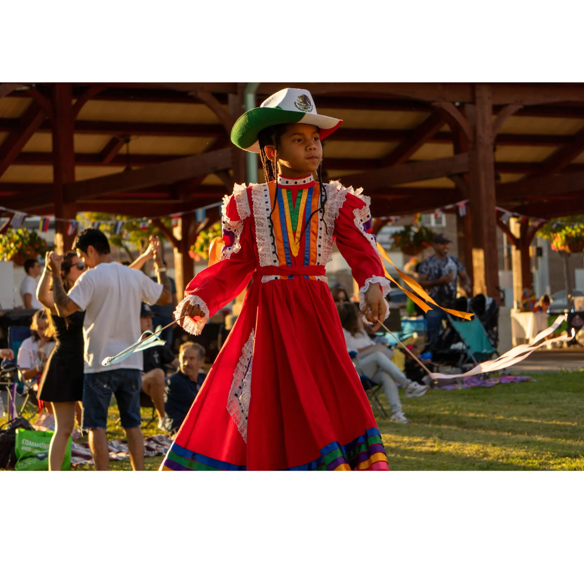 A young dancer in a red folklorico dress performing at Noche de Fiesta