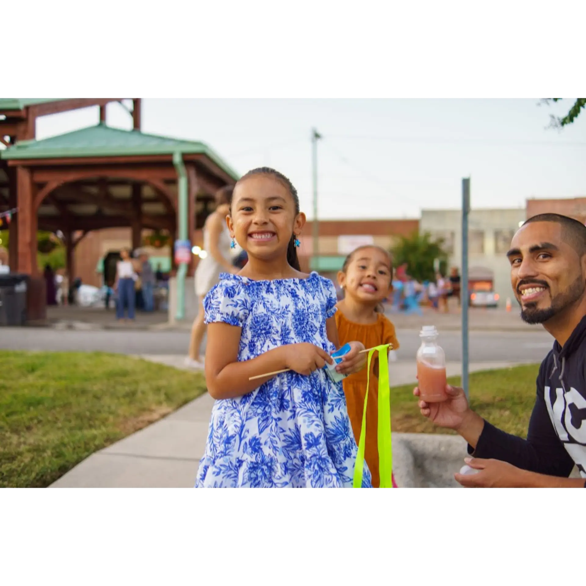 A dad and his daughters smiling at Noche de Fiesta